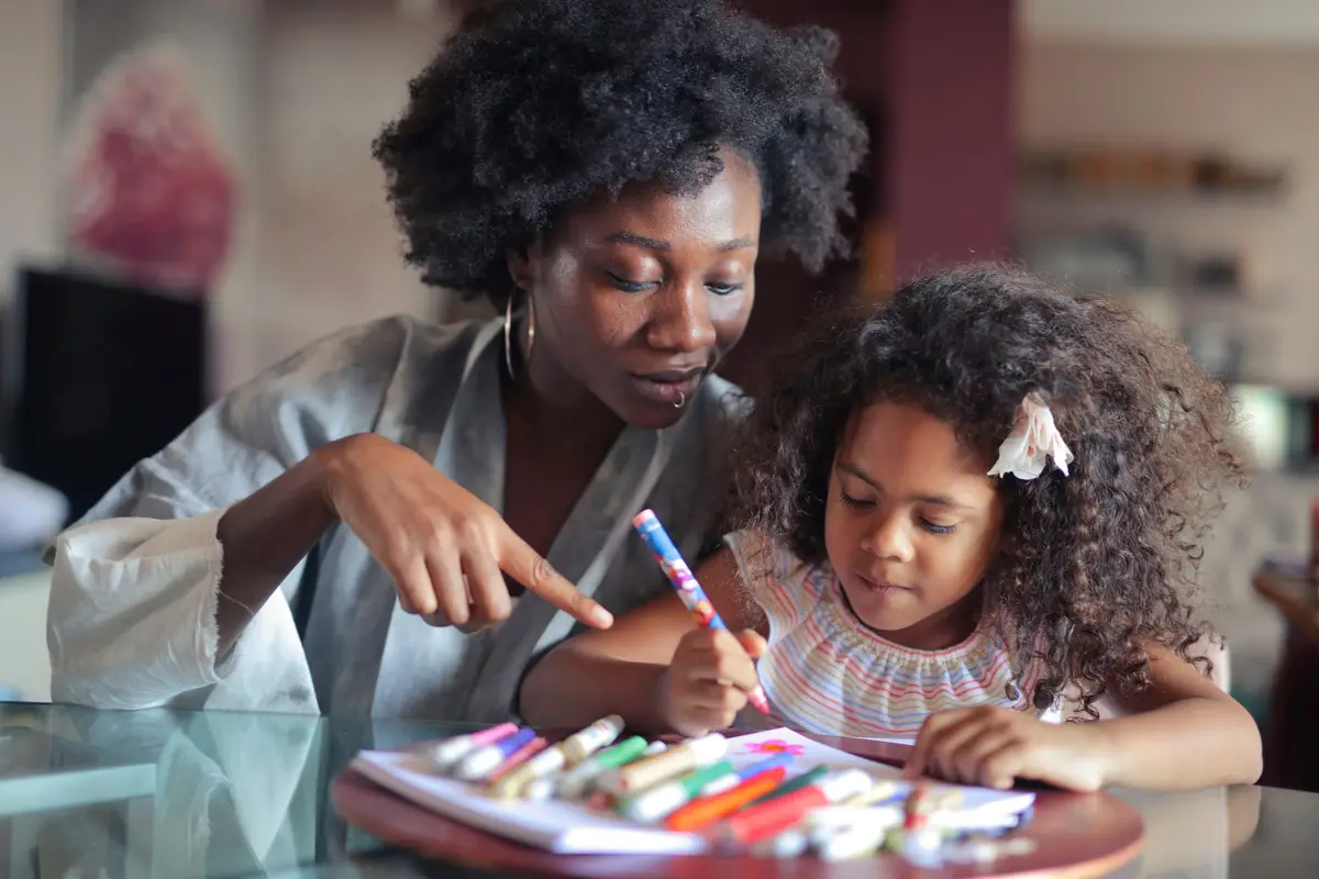 A nanny helping a young girl with colouring